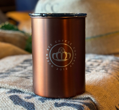 Rose gold tumbler with a logo on a textured surface